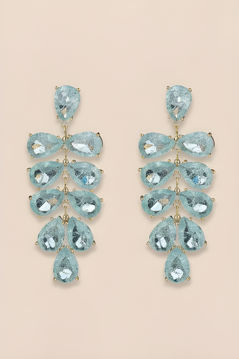Pair of turquoise teardrop earrings on a beige background