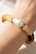 Beaded bracelet with pearls and tortoiseshell beads on a wrist against a neutral background