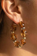 Close-up of an ear wearing a brown beaded hoop earring.