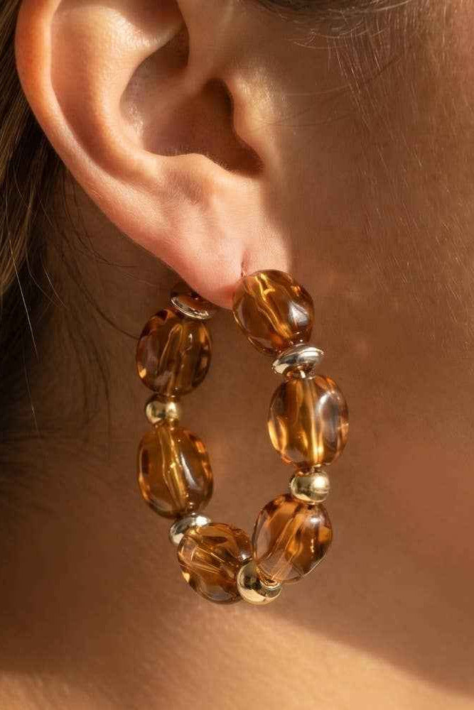 Close-up of an ear wearing a brown beaded hoop earring.