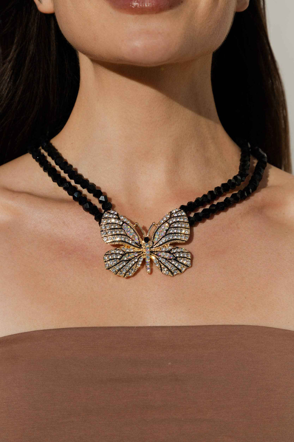 Butterfly pendant necklace on a person with a neutral background