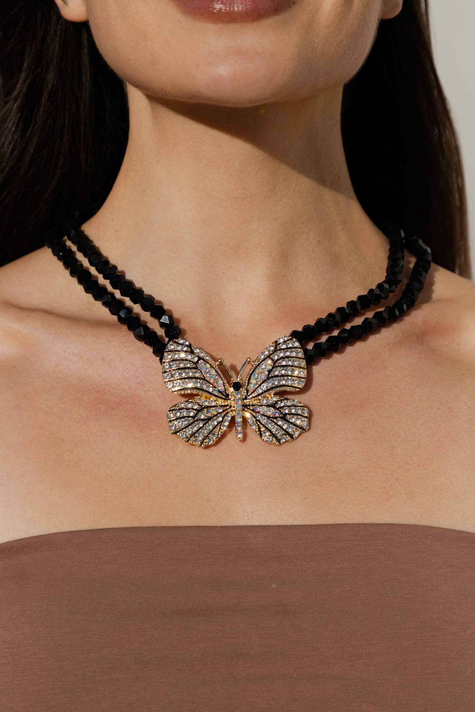 Butterfly pendant necklace on a person with a neutral background