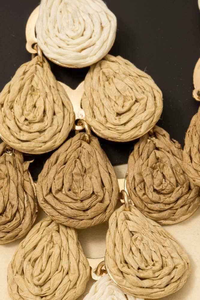 Close-up of a necklace with beige woven pendants on a dark background