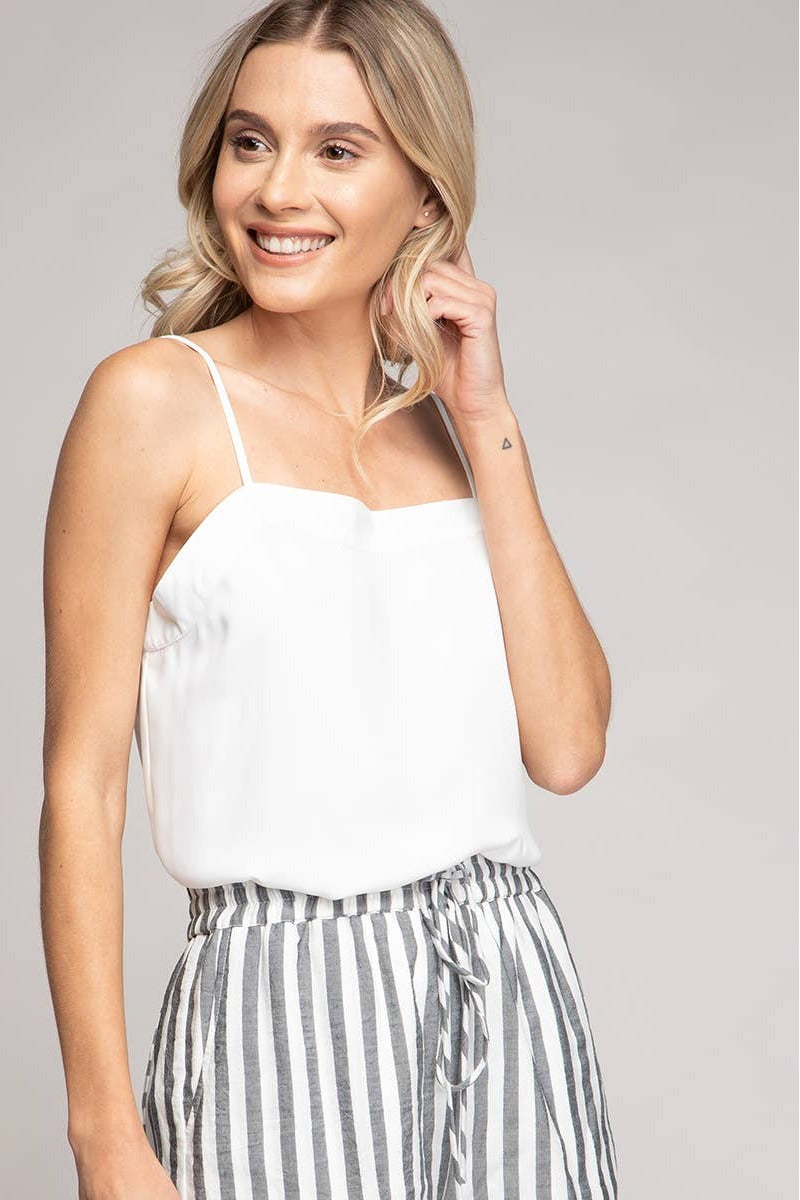 Woman wearing a white top and striped pants against a plain background