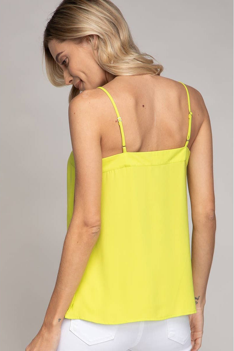 Woman wearing a yellow tank top against a neutral background