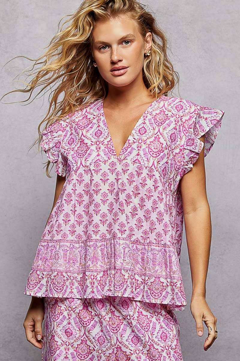 Woman wearing a pink patterned top and pants against a gray background