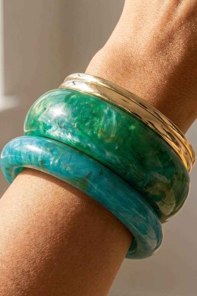 Green bangles on a wrist with a blurred background