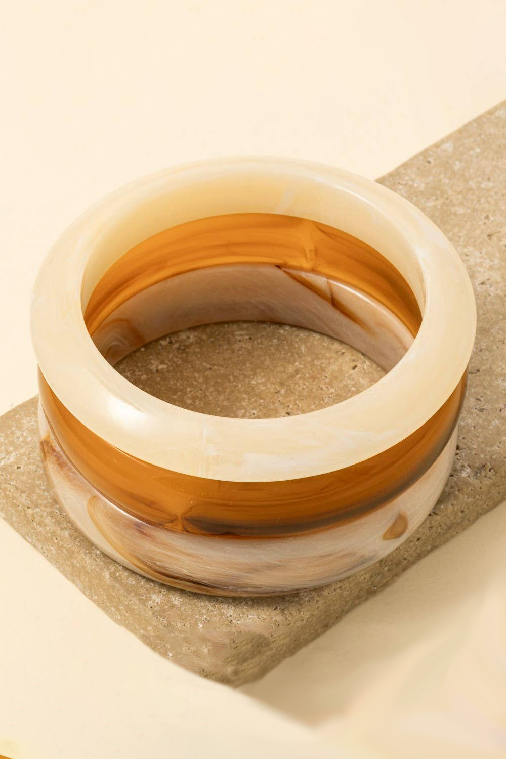 Decorative bowl with brown and beige stripes on a textured surface