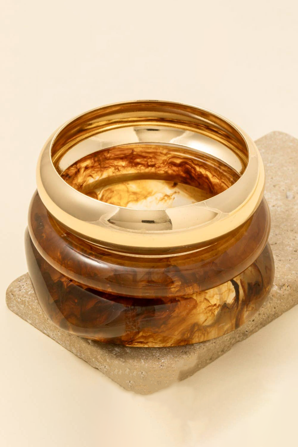 Gold and tortoiseshell ring on a beige stone surface