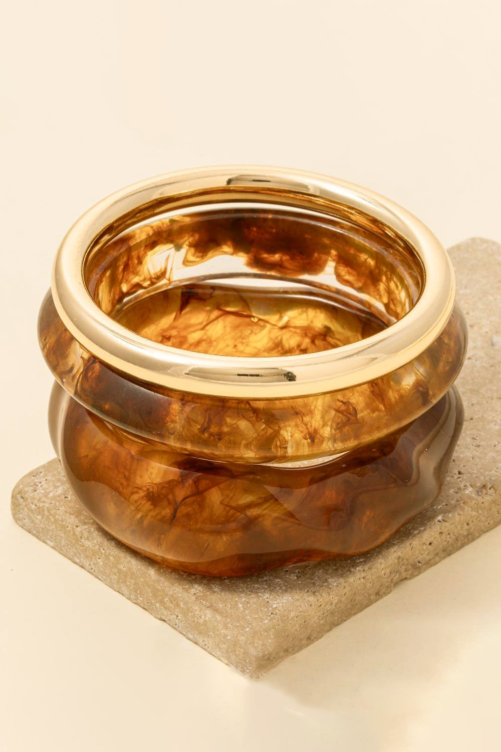 Gold ring with a textured design on a beige stone surface