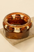 Brown glass ring with gold accents on a beige stone surface
