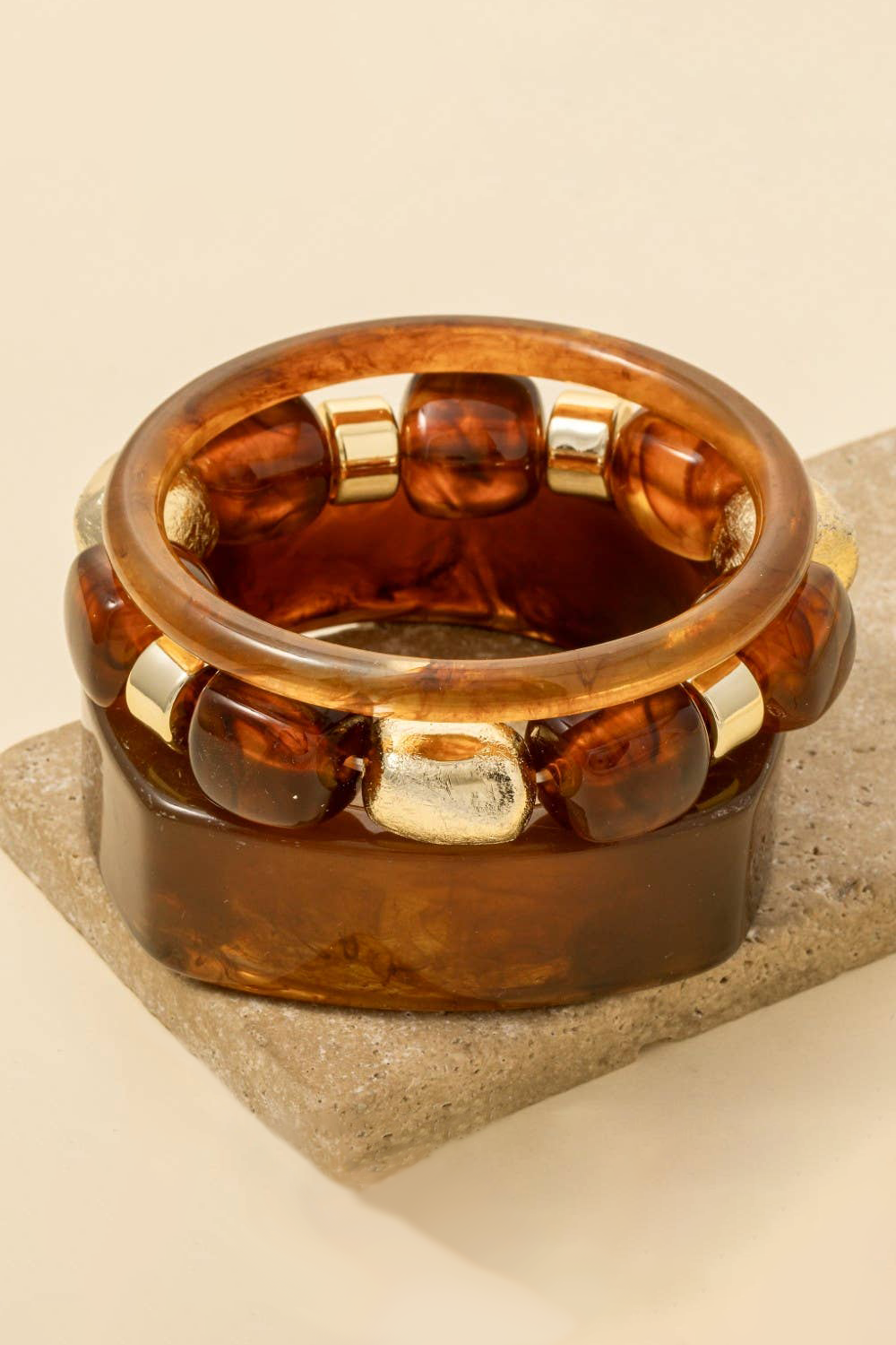Brown glass ring with gold accents on a beige stone surface