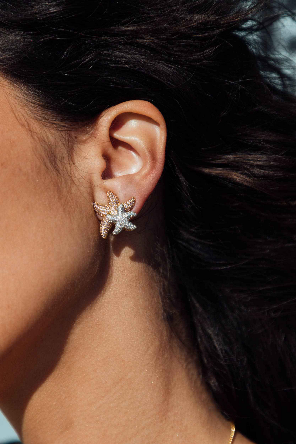 Close-up of an ear wearing a star-shaped earring with a blurred background