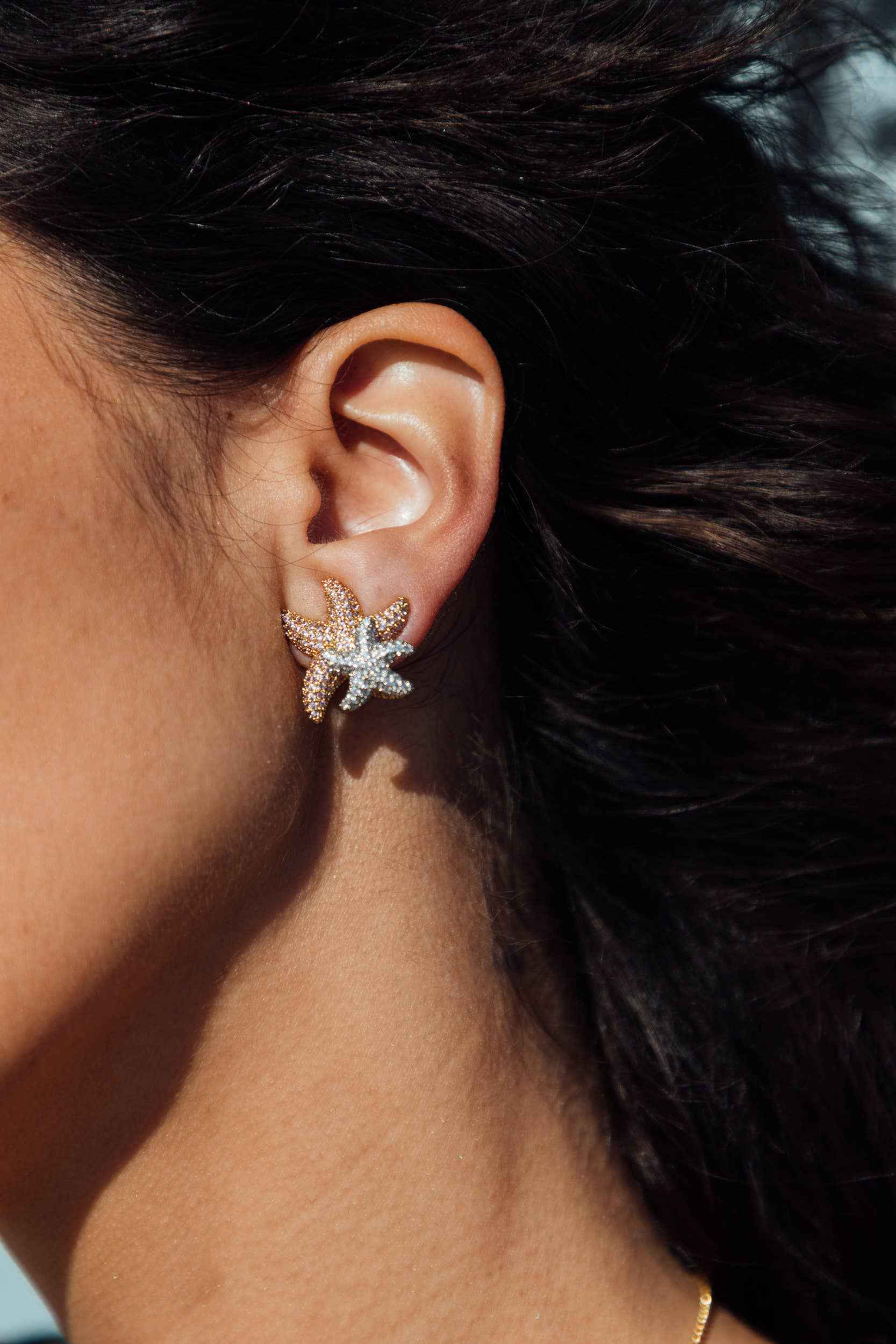 Close-up of an ear wearing a star-shaped earring with a blurred background