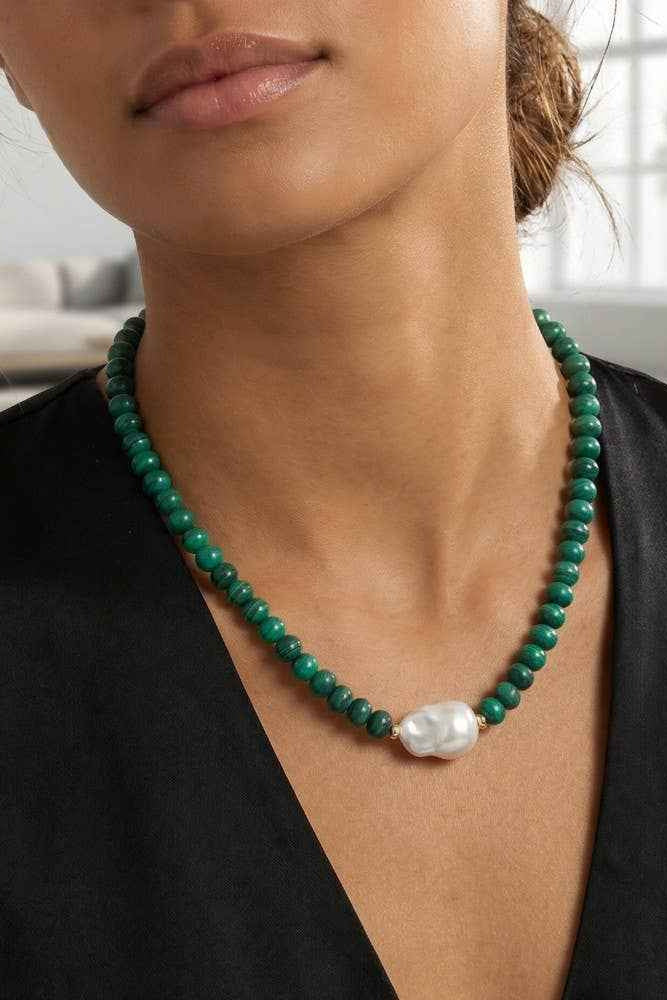 Close-up of a person wearing a green beaded necklace with a pearl accent.