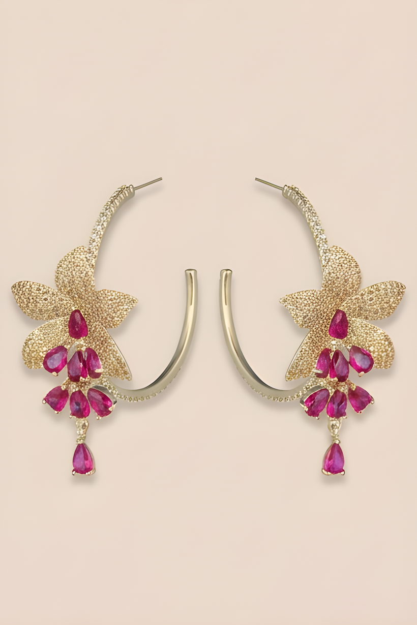 Gold hoop earrings with pink gemstones on a beige background