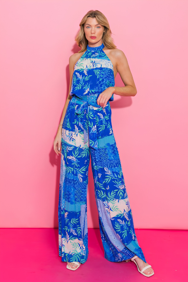 Woman wearing a blue floral jumpsuit against a pink background