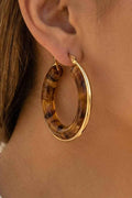 Hoop earrings with tortoiseshell pattern worn by a person