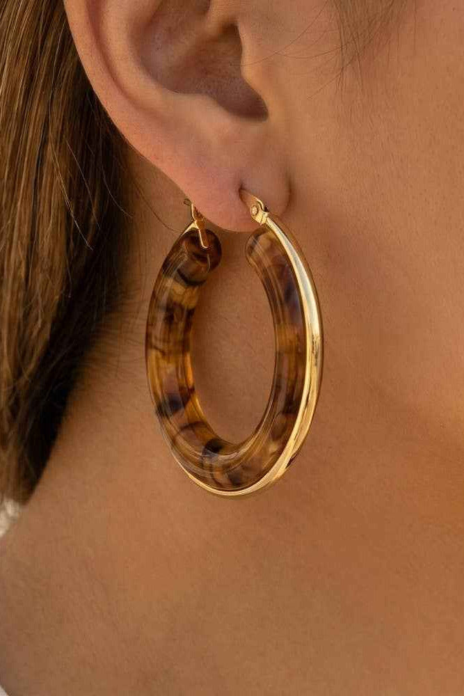 Hoop earrings with tortoiseshell pattern worn by a person