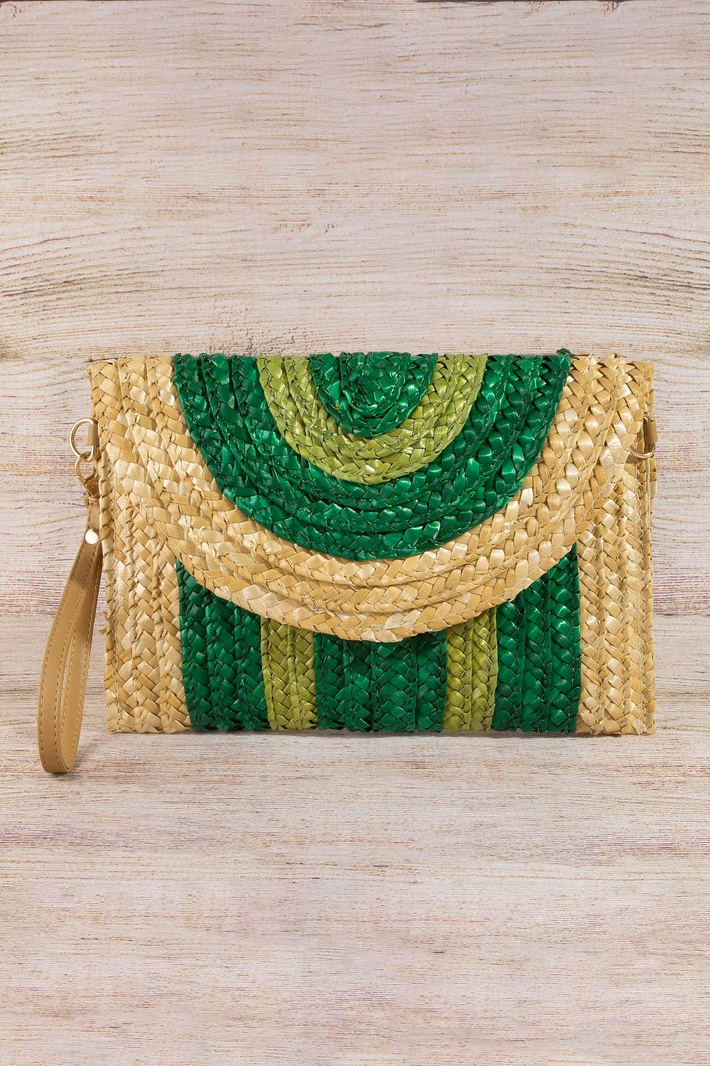 Woven clutch bag with green and gold pattern on a wooden surface