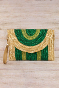 Woven clutch bag with green and gold pattern on a wooden surface