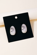 Pair of silver earrings on a black card with a white background