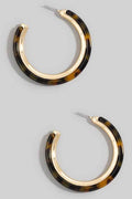 Pair of tortoiseshell hoop earrings on a gray background