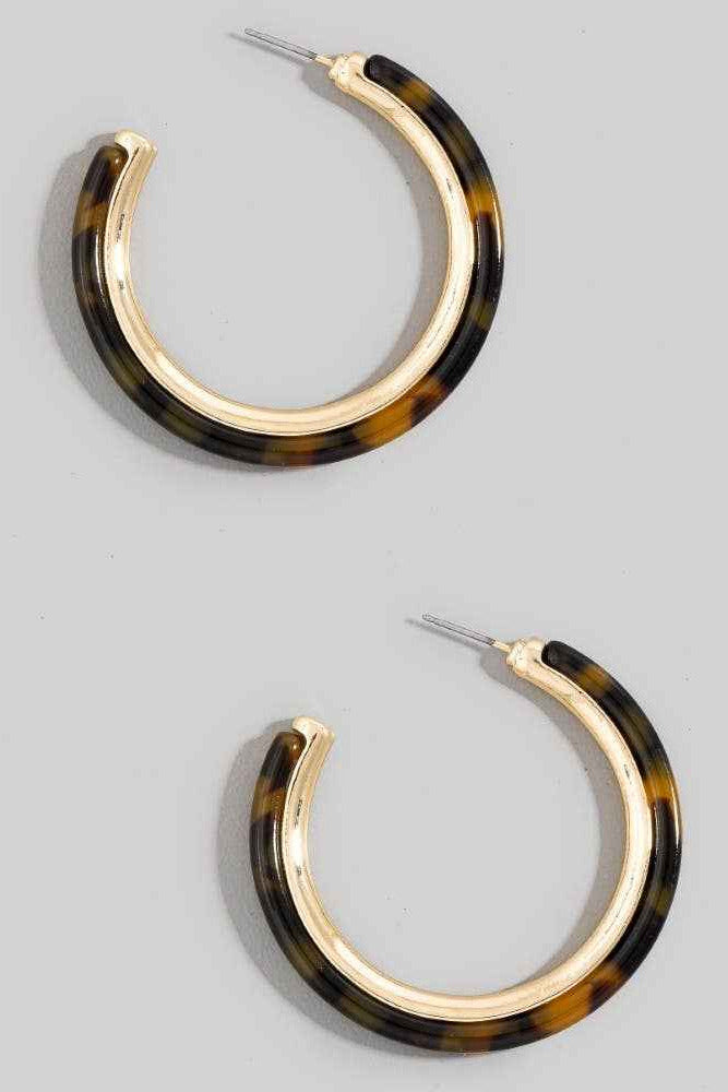 Pair of tortoiseshell hoop earrings on a gray background