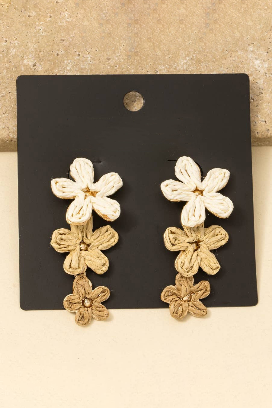 Floral earrings on a black card with a beige background