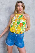Woman wearing a floral top and denim shorts against a textured gray wall