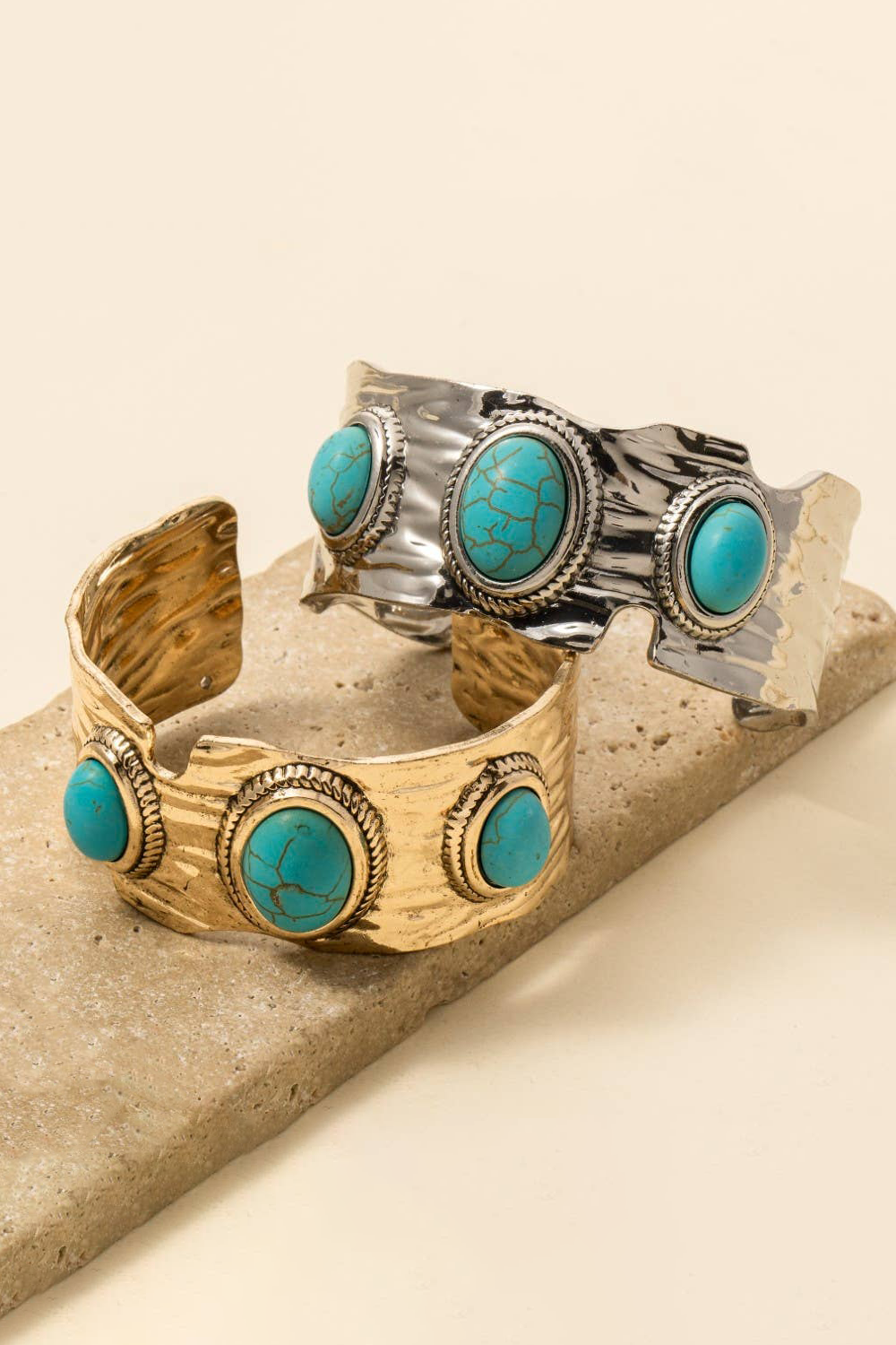 Two bracelets with turquoise stones on a beige surface