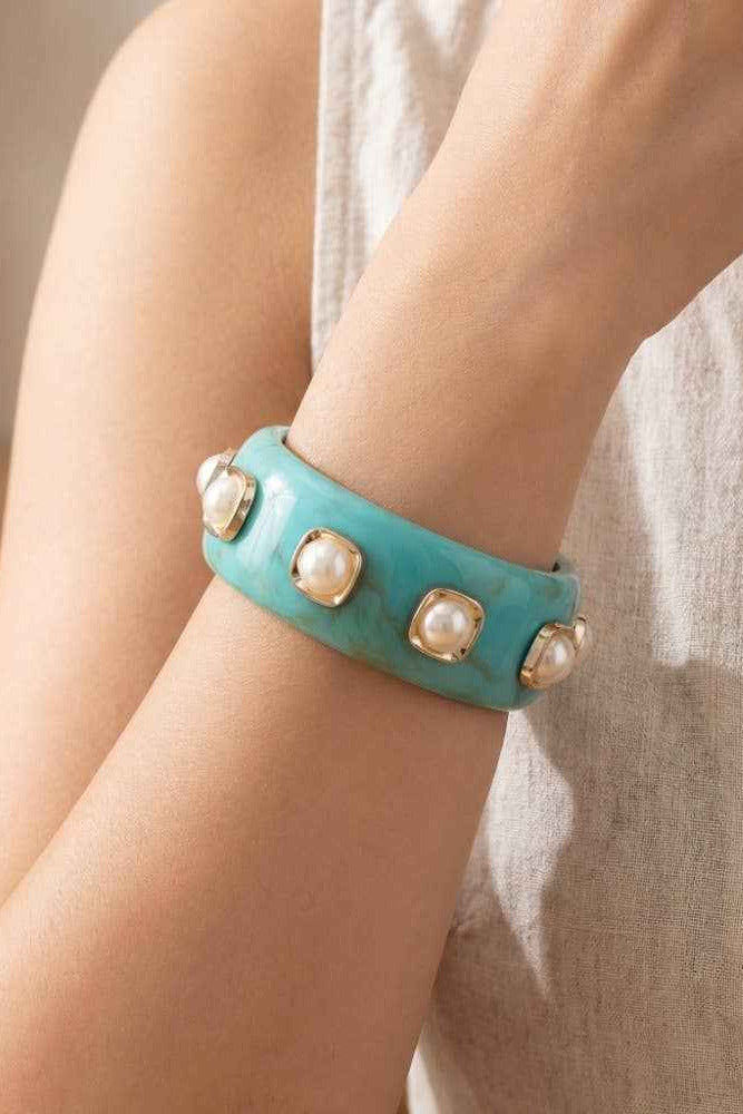 Turquoise bracelet with pearl-like embellishments on a wrist